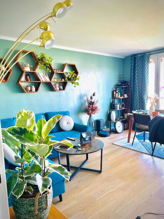un salon bleu avec un canapé bleu et une table dans l'établissement Un Cocon Vert Canard à côté Paris 14ème - 3 pièce de 70m2 avec 2 chambres et un grand salon lumineux, à Montrouge