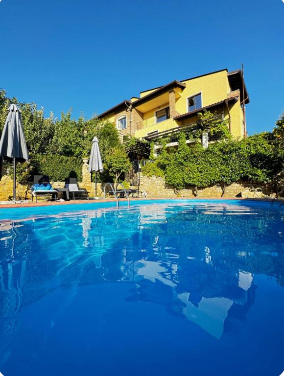 a large blue swimming pool with a house in the background at Province Stone House Varna in Varna City