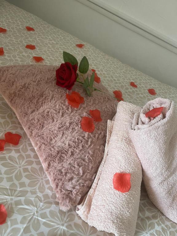 - une paire de serviettes avec une rose sur un lit dans l'établissement Le repos poitevin Un brin romantique, à Vivonne