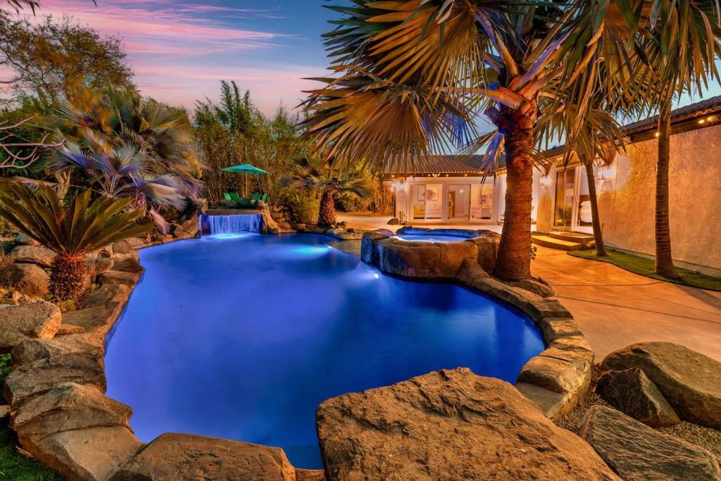 a swimming pool in a backyard with palm trees at NEW LUXURY ESTATE - Sleeps 22 - Saltwater Pool, Spa, Waterfall With Cave Grotto! in Vista