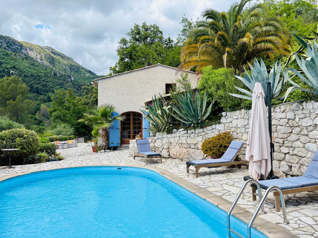 une piscine avec deux chaises et un parasol à côté d'une maison dans l'établissement Villa au charme incroyable et piscine, à Saint-Jeannet