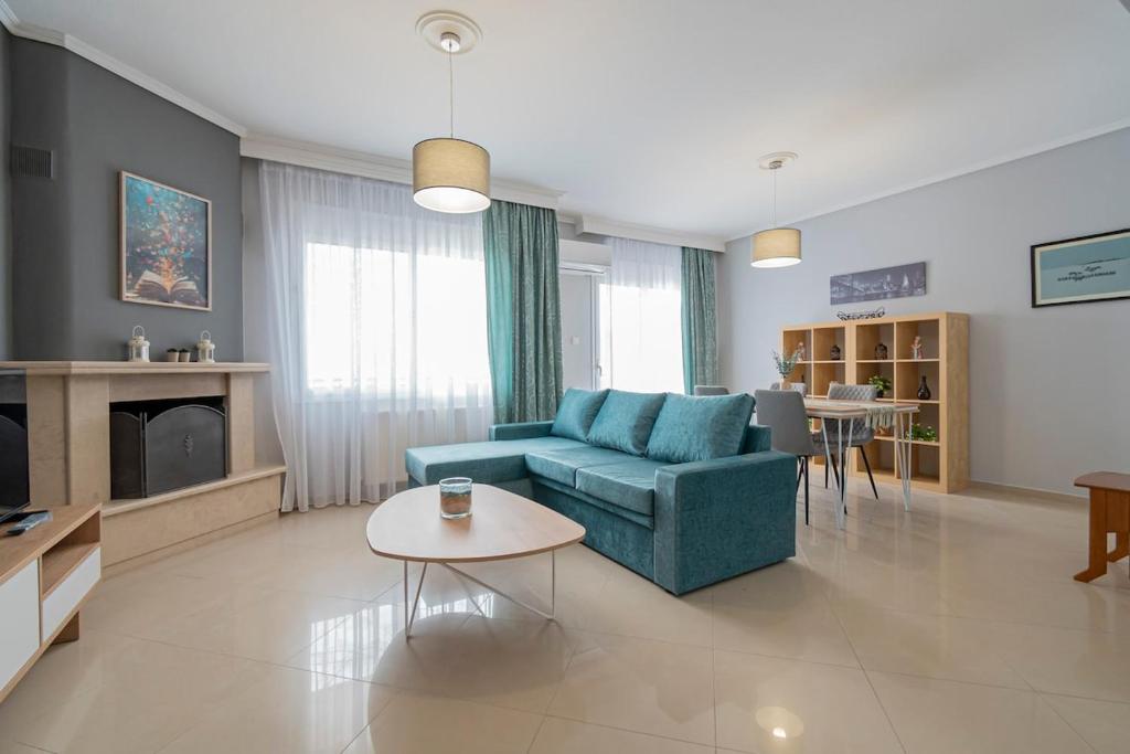 a living room with a blue couch and a table at M&P Apartment by RentalsPro - Nea Moudania Halkidiki in Nea Moudania