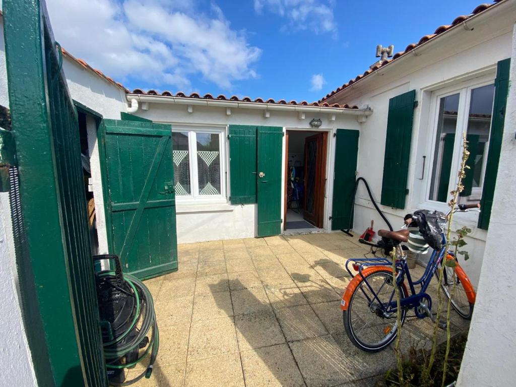 een fiets geparkeerd buiten een huis met groene deuren bij Départ du Marin à la Cotinière in Saint-Pierre-dʼOléron