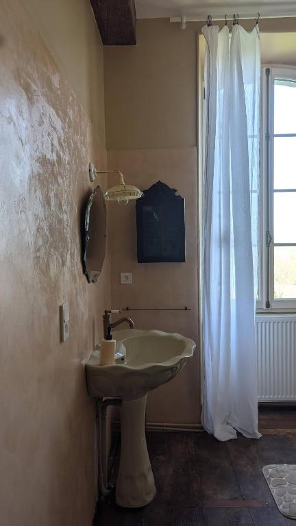une salle de bain avec un lavabo et une fenêtre dans l'établissement Maison Nathis, à Saint-Sulpice-de-Roumagnac