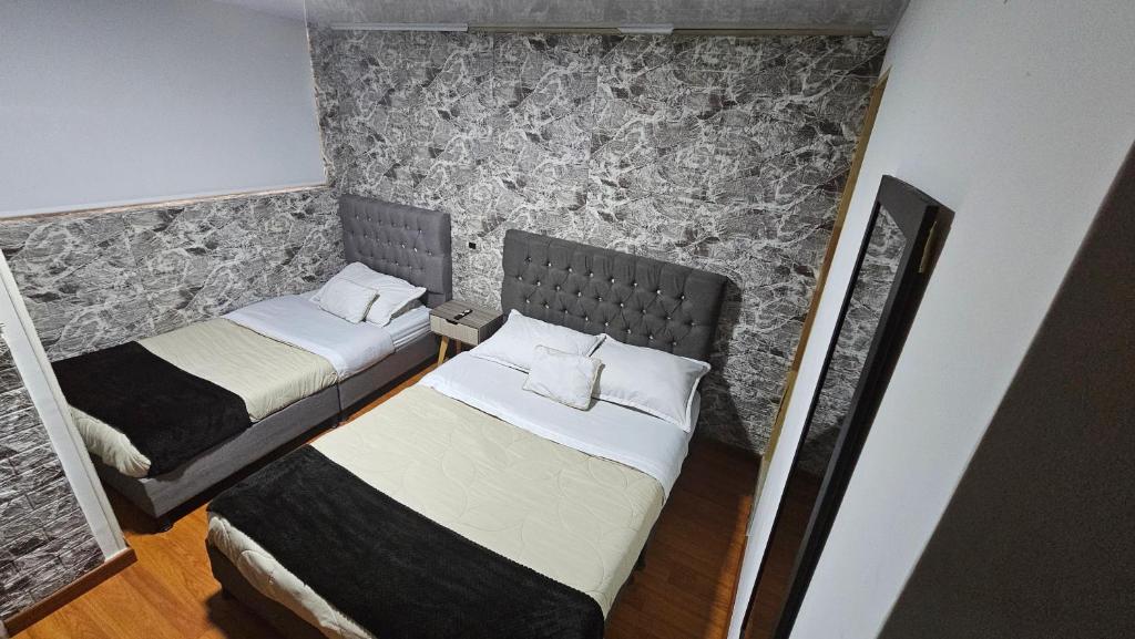 two beds in a small room with a wall at Colisseum Roma - Vive Claro -El cubo movistar campin in Bogotá