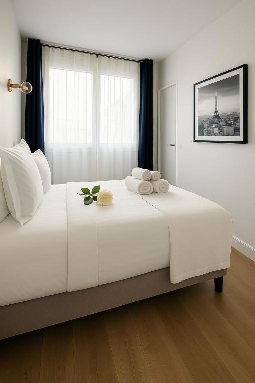 une chambre avec un grand lit blanc avec des serviettes dessus dans l'établissement Paris Grenelle Suite Champs de Mars, à Paris