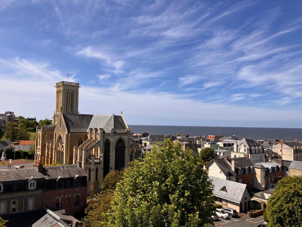 un vieux bâtiment avec une tour d'horloge dans une ville dans l'établissement Appartement 2 pièces centre de Villers-sur-Mer avec parking - FR-1-712-40, à Villers-sur-Mer