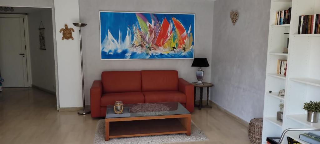 un salon avec un canapé rouge et un tableau dans l'établissement Le Pavillon de Flore, à Antibes