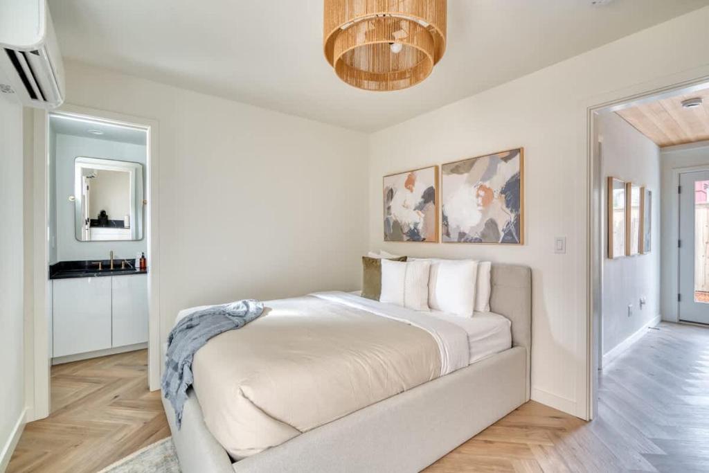 a white bedroom with a large bed and a chandelier at Stay Portland - Alberta Arts District Hideaway - Stylish Studio in Portland
