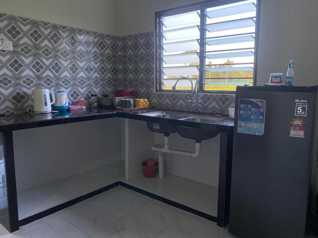 a kitchen with a counter with a sink and a window at Najib homestay in Kampong Terus