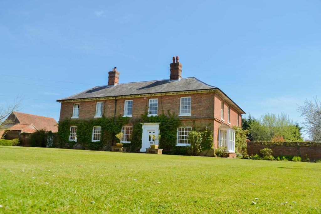 une grande maison en briques sur un champ herbeux dans l'établissement Sankence lodge, à Aylsham