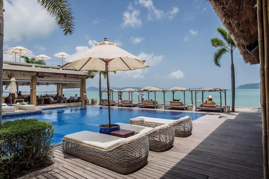 a resort swimming pool with chairs and an umbrella at NEW Malee Resort Studio 858 in Rawai Beach