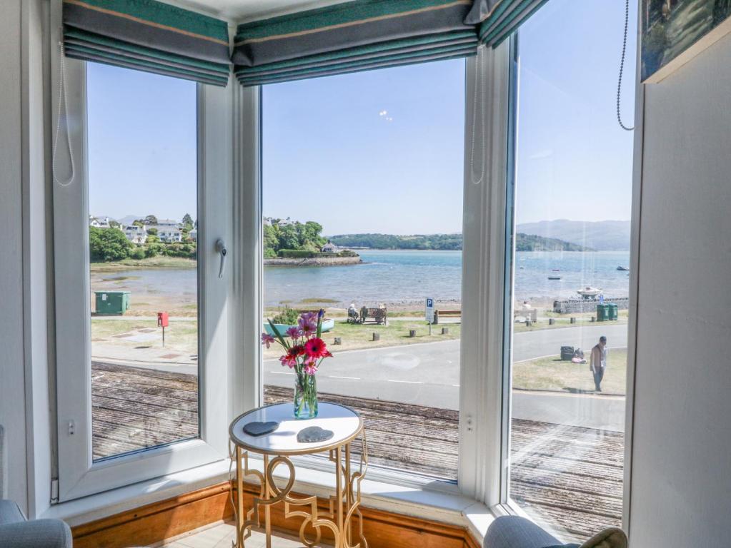 a room with a large window with a table and chairs at Bay View Apartment in Porthmadog