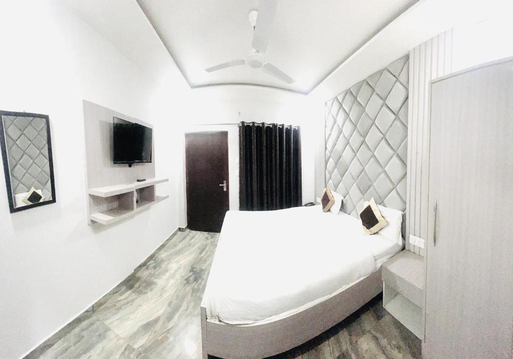 ein weißes Schlafzimmer mit einem Bett und einem Fernseher in der Unterkunft Hotel Green Apple BAREILLY in Bareilly