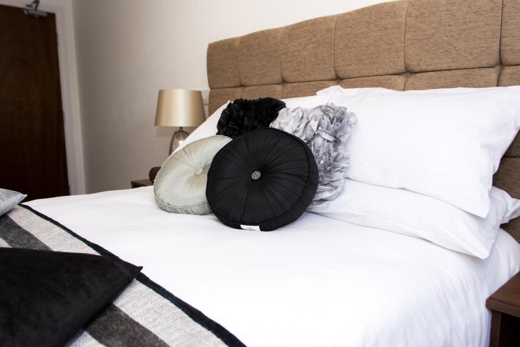 a bed with several pillows on it with a black and white at Trivelles Mayfair,stockport in Manchester