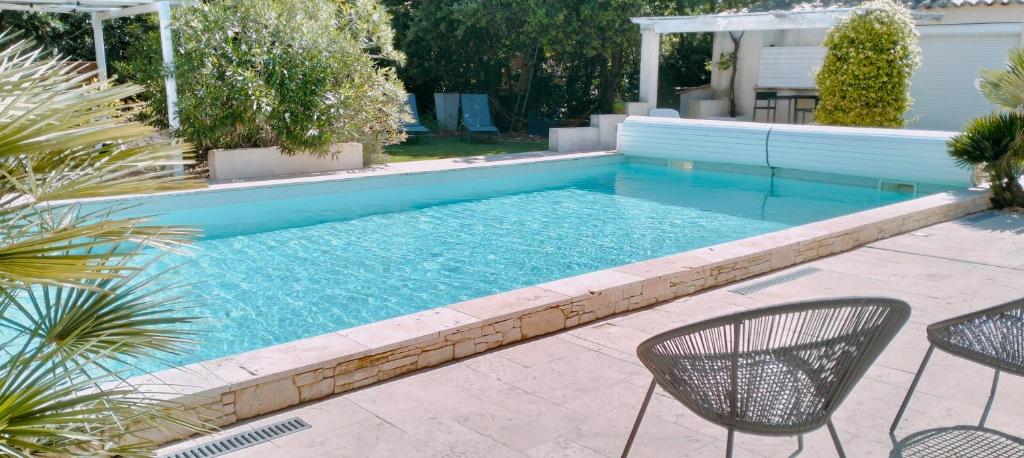 une piscine avec deux chaises et une table dans l'établissement Gîte Chez Erika et Mathias, à Grignan
