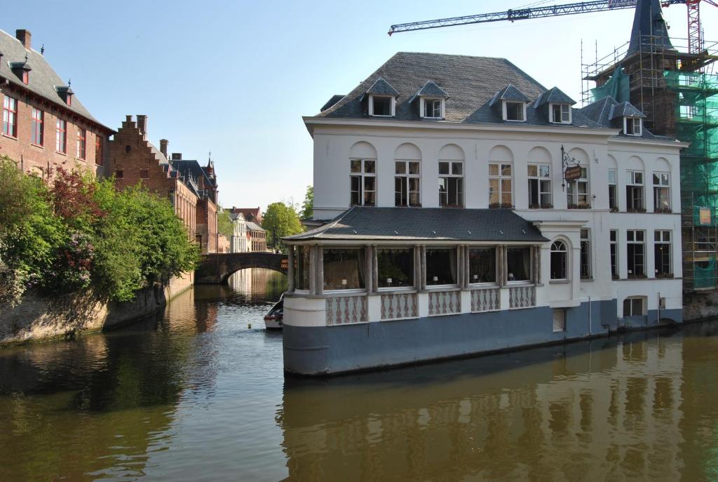 a house boat on a river in a city at Hotel Duc De Bourgogne in Bruges