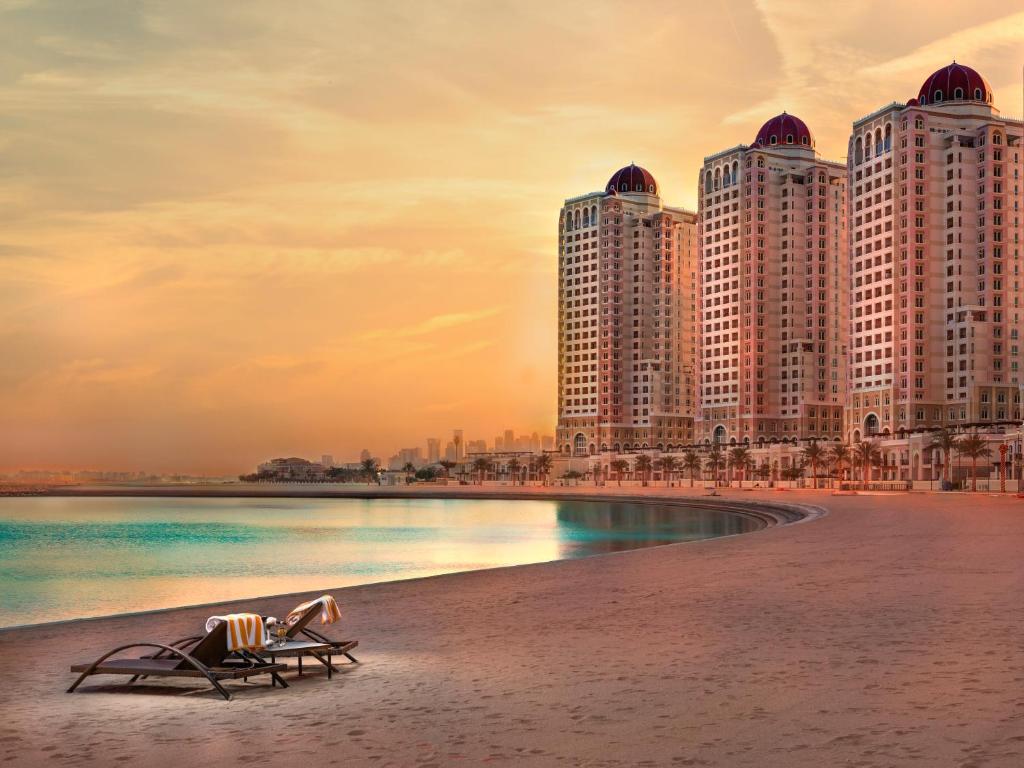 due sedie su una spiaggia con alti edifici di Retaj Baywalk Residence a Doha