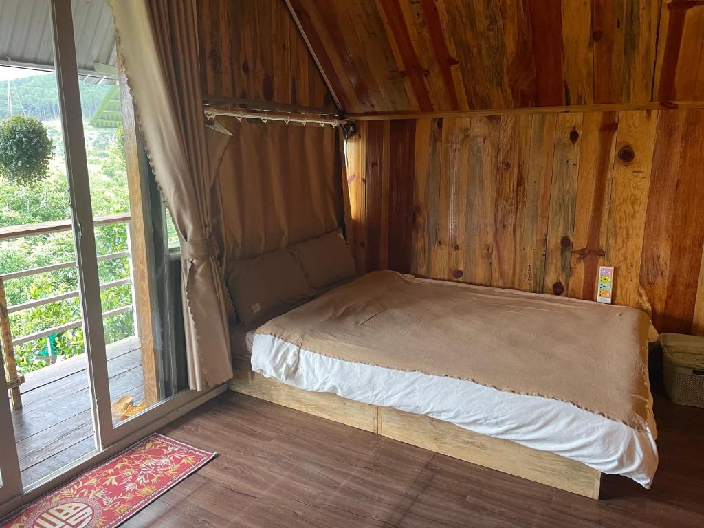 un piccolo letto in una camera in legno con finestra di Homestay Đồi Sương Trắng a Kon Rung (1)