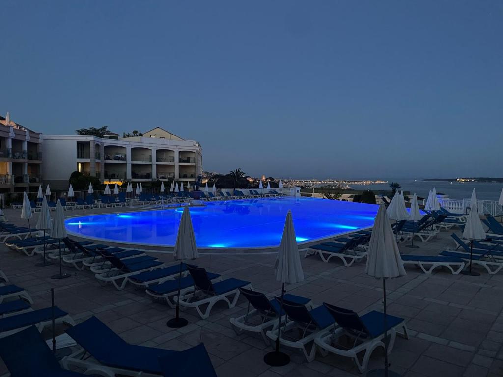 une grande piscine avec chaises et parasols dans l'établissement Résidence de charme avec piscine à débordement, à Cannes