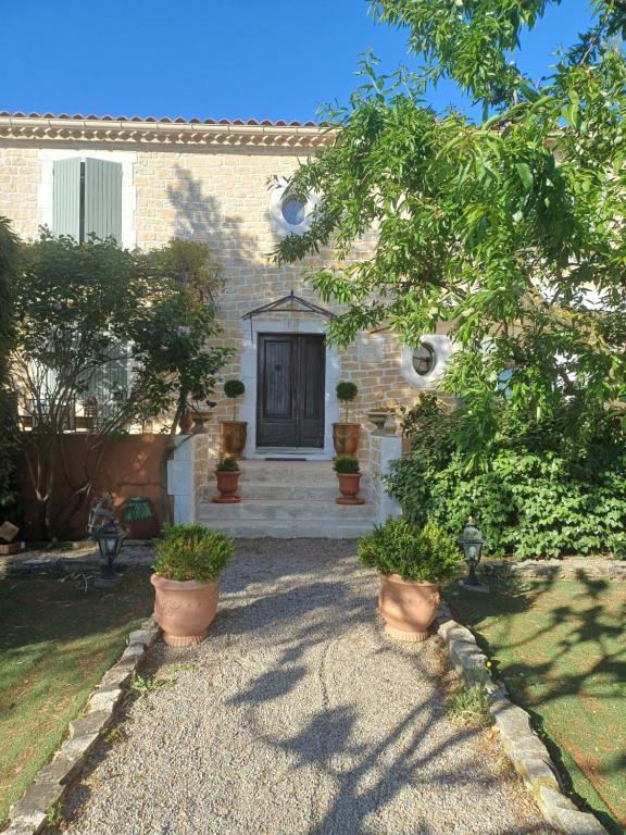 une maison avec une porte et quelques plantes dans une cour dans l'établissement Gite Au fond du jardin, à Saint-Saturnin-lès-Avignon