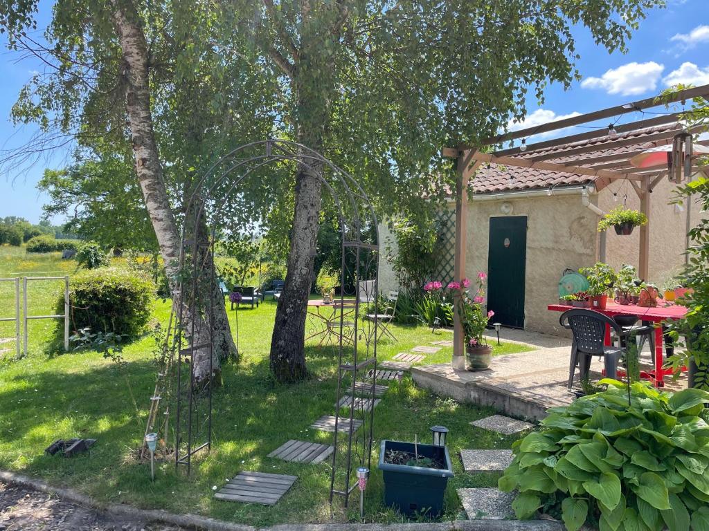 - un jardin avec une table et des chaises en face d'une maison dans l'établissement STUDIO EN AUVERGNE Le ruisseau, à Saint-Priest-Bramefant