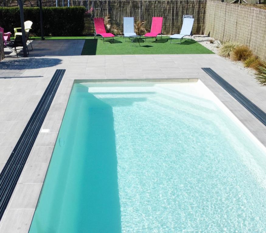 une piscine bleue avec des chaises roses dans un jardin dans l'établissement Gîte à la campagne 1, à Cérans-Foulletourte