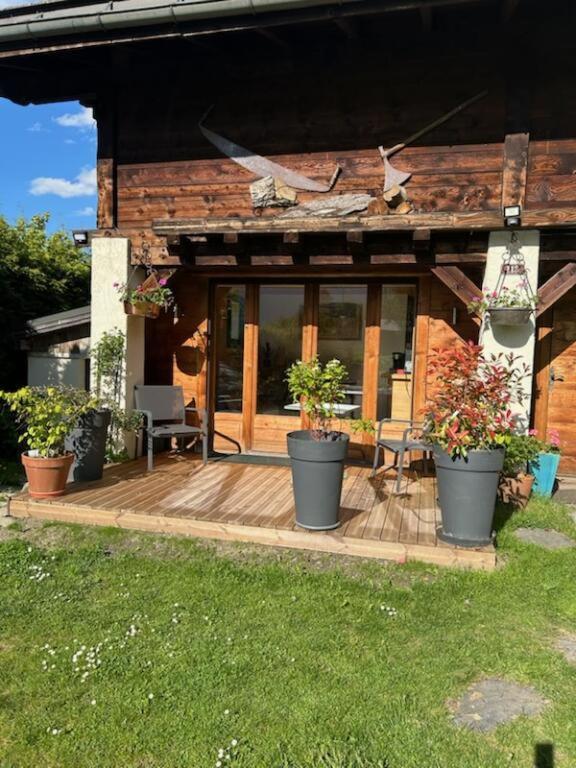 une maison avec des plantes en pot sur une terrasse en bois dans l'établissement Beau studio dans la vallée de CHAMONIX, aux Houches