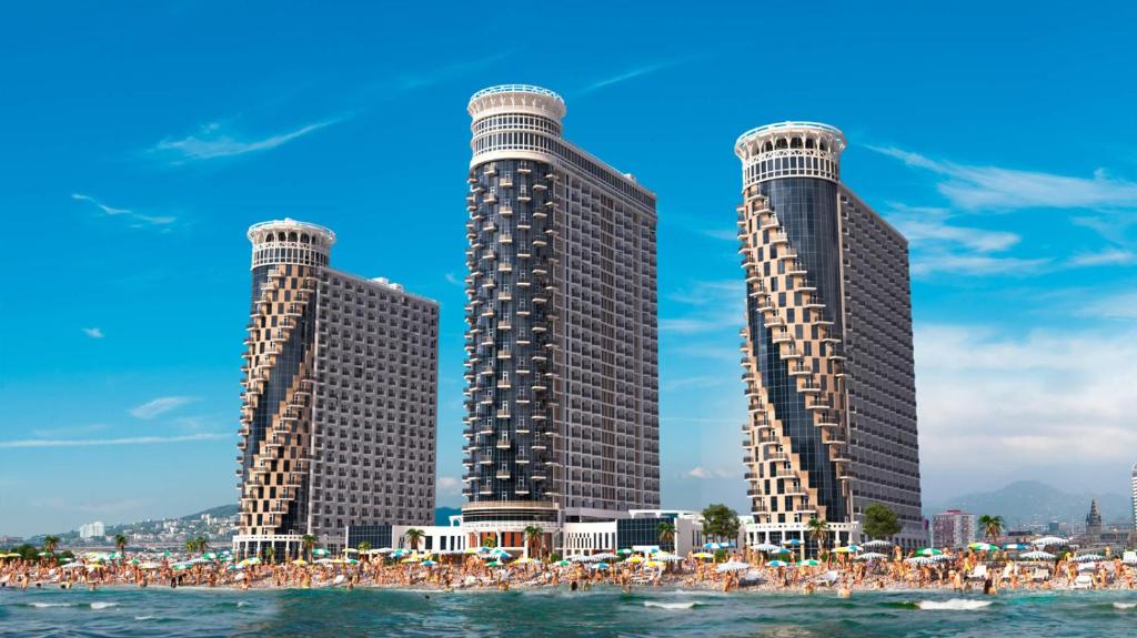 un grupo de personas en la playa frente a los edificios en Seaview Panoramic Apartments ORBI Sea Towers Batumi, en Batumi