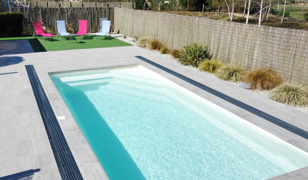 - une piscine dans un jardin avec des chaises roses dans l'établissement Gîte à la campagne 3, à Cérans-Foulletourte
