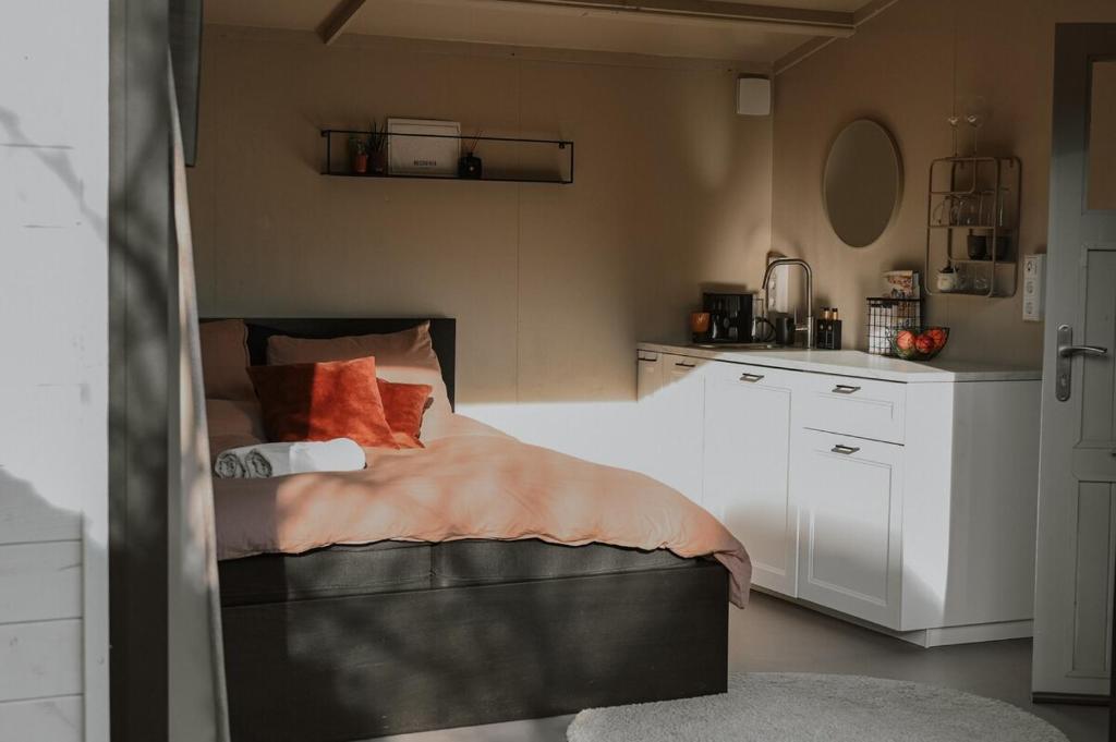 a small bedroom with a bed and a kitchen at Badhuisje aan Zee op Huisduinen in Huisduinen
