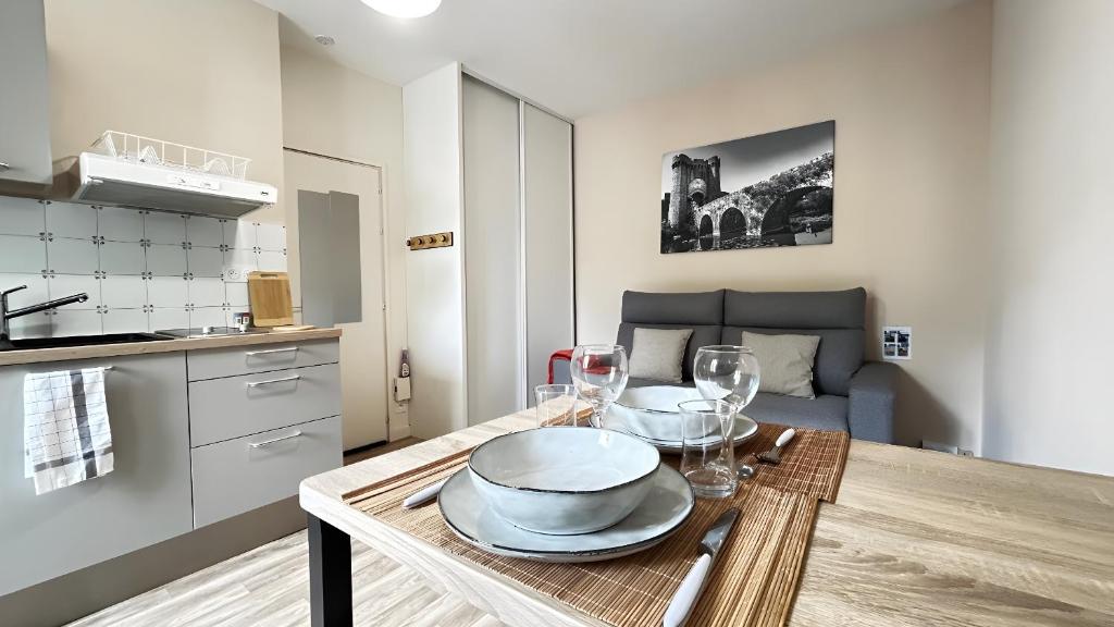 une cuisine avec une table avec des assiettes et des verres à vin dans l'établissement Studio proche centre et gare, à Parthenay
