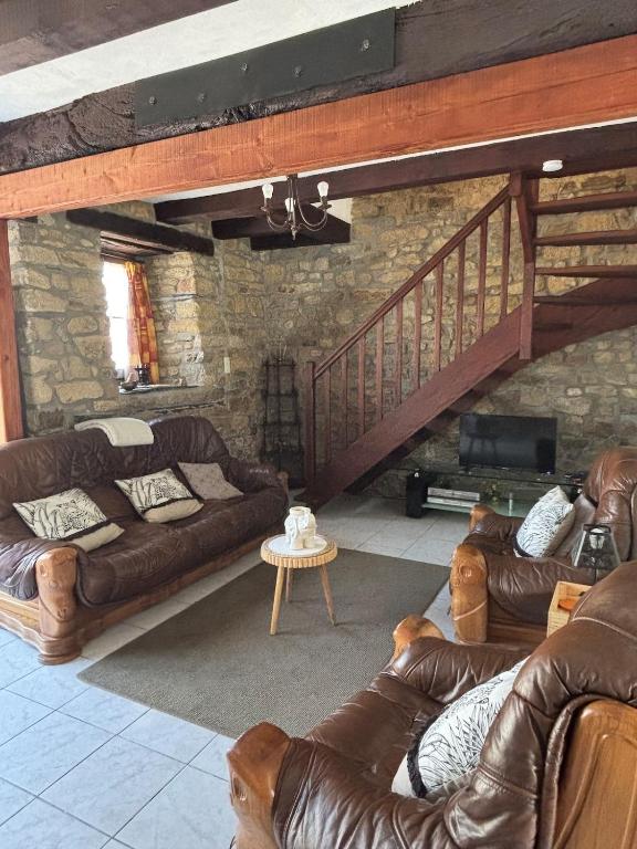 - un salon avec des canapés en cuir et un escalier dans l'établissement Repos de l'Île aux Pies, à Saint-Vincent-sur-Oust
