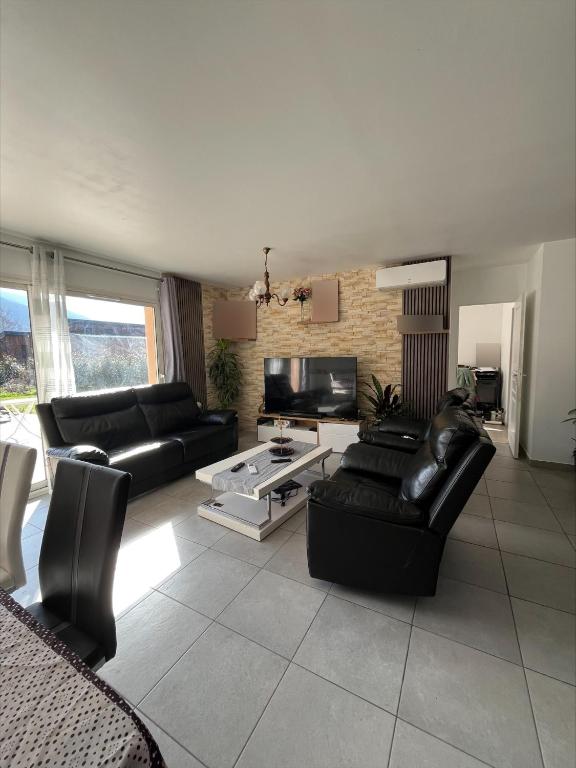 Il comprend un salon doté d'un mobilier en cuir noir et d'une télévision. dans l'établissement Maison familiale dans les Pyrénées -option piscine, à Chaum