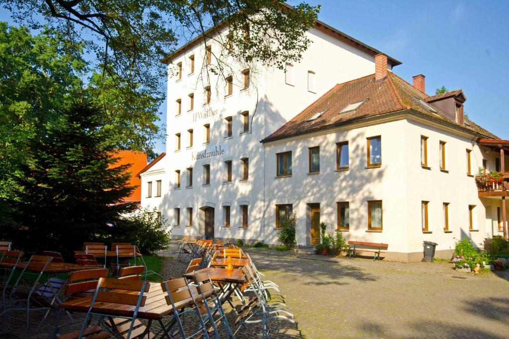 - un grand bâtiment blanc avec des chaises devant dans l'établissement Ferienwohnung Zur Mühle beim Playmobil Fun Park Zirndorf, à Zirndorf