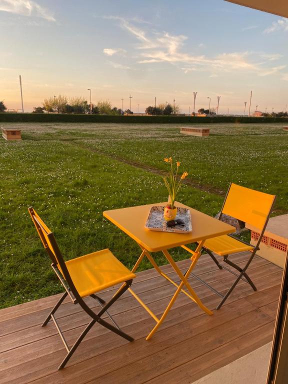 une table et deux chaises sur une terrasse avec un champ dans l'établissement Front de Mer, à Calais