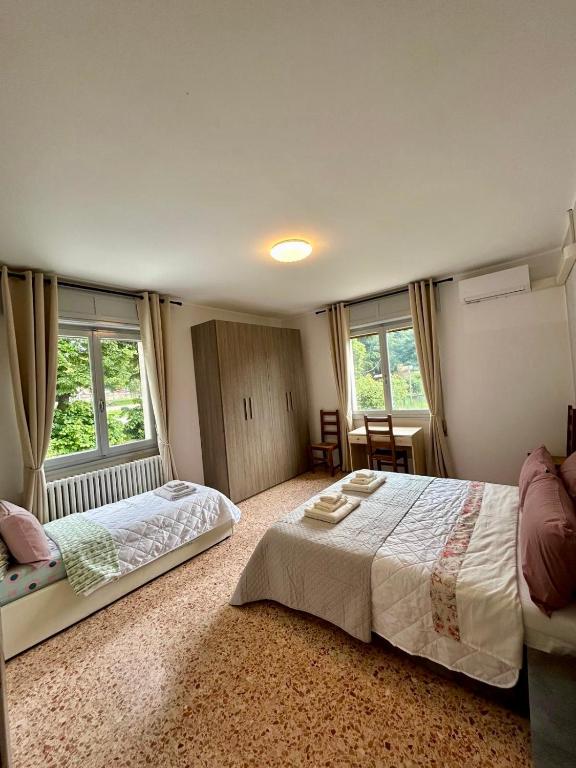 a bedroom with a large bed and two windows at B&B a San Michele da Maja in Gardone Riviera