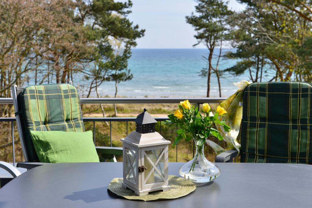 a table with a vase of flowers and a lamp at Ferienwohnung Admiralssuite in Juliusruh