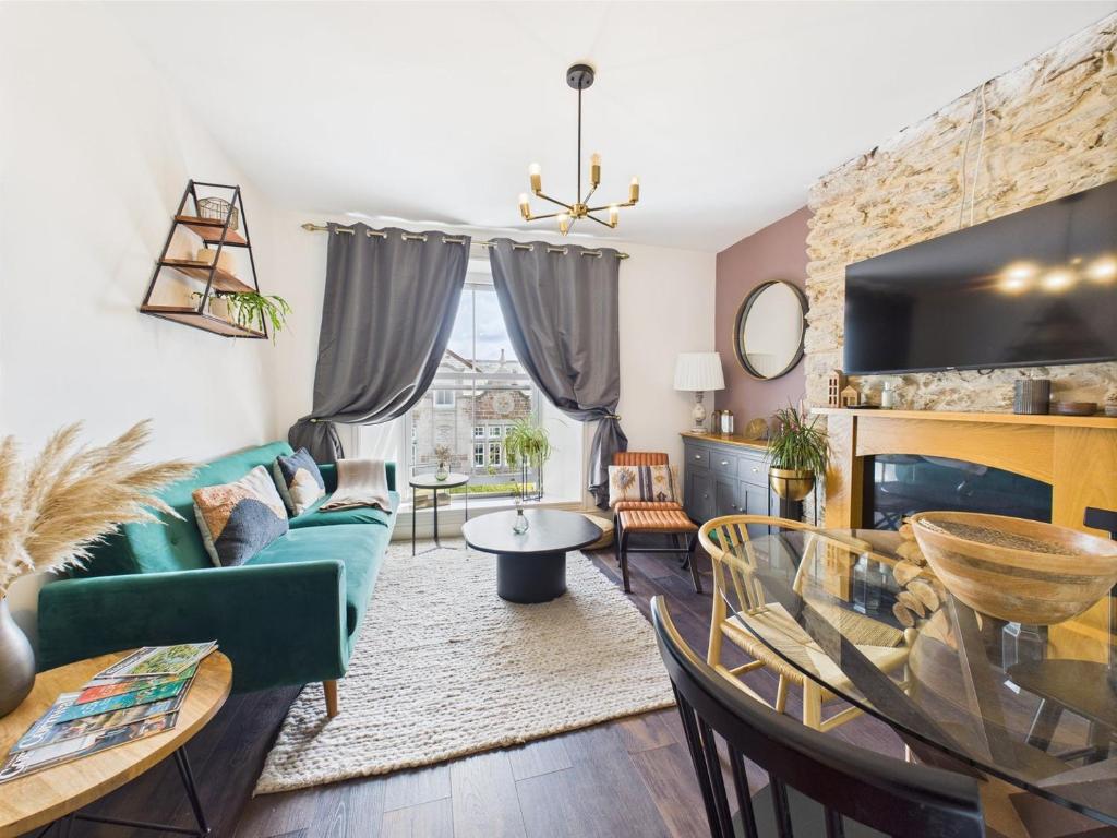 a living room with a green couch and a table at Elegant 1-Bed Apt | Central Falmouth | Parking & WiFi | Lockbox Entry | Walk to Town & Pubs | Quiet Residential Road | Top Floor Apartment | Near Train Stations & Beaches in Falmouth