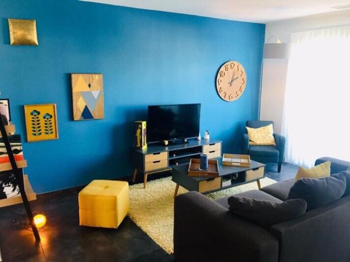 un salon bleu avec un canapé et une horloge au mur dans l'établissement Maison proche de Perpignan et de la mer, à Pia