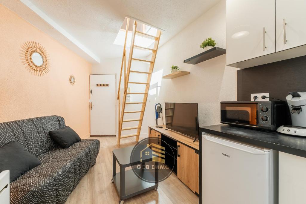 Il comprend un salon doté d'un canapé et une cuisine équipée d'un four micro-ondes. dans l'établissement Le Petit Saint Paul, à Grenoble
