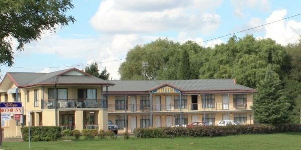 a large house with a porch on a field at Elite Motor Inn in Armidale