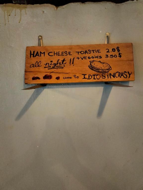 un cartello di legno appeso a un muro di Idiosyncrasy Bar and Hostel a Kampot