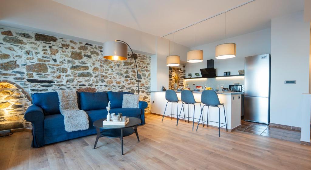 a living room with a blue couch and a stone wall at Casita in Ermoupoli