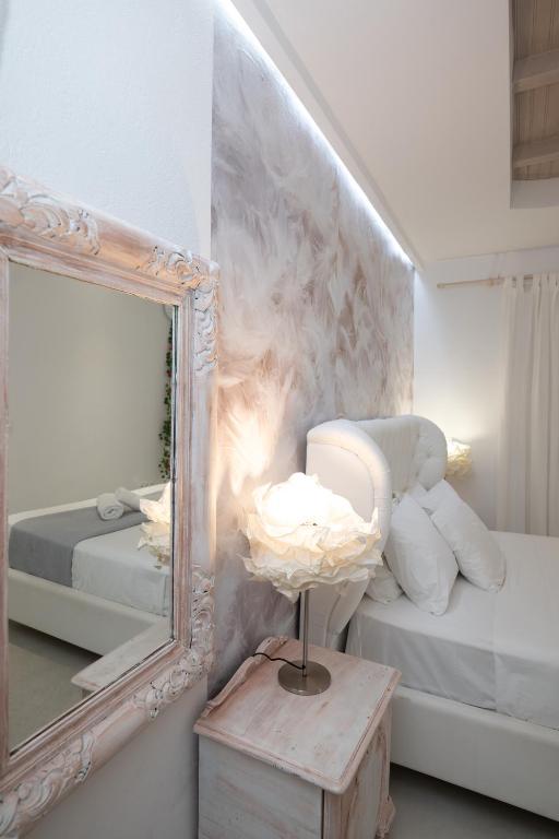 a mirror and a lamp on a table next to a bed at Almyra Home in Ornos