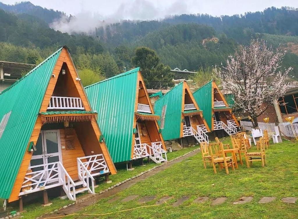 eine Reihe von Holzhütten mit Tischen und Stühlen in der Unterkunft Kaira huts in Manali