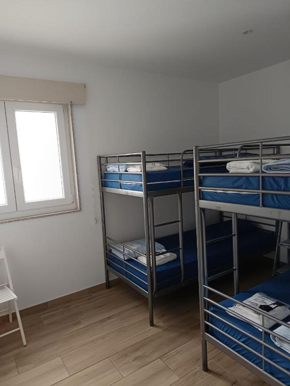 Pokój z 3 łóżkami piętrowymi i oknem w obiekcie Albergue Casa Manola w mieście Abeleiras