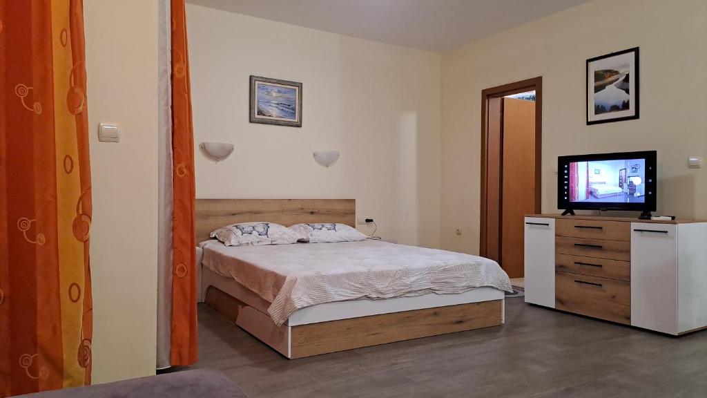 Un dormitorio con una cama y un televisor de pantalla plana. en Nestinarka beach studio, en Tsarevo