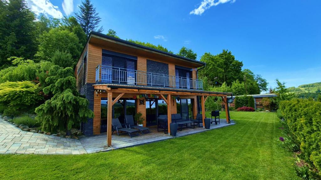 a house with a deck on a lawn at Zenovna - Reset v Beskydech in Frýdlant nad Ostravicí