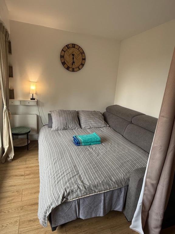 une chambre avec un lit et une horloge au mur dans l'établissement Studio rénové 100m plage - Grand balcon - Parking, à Villers-sur-Mer